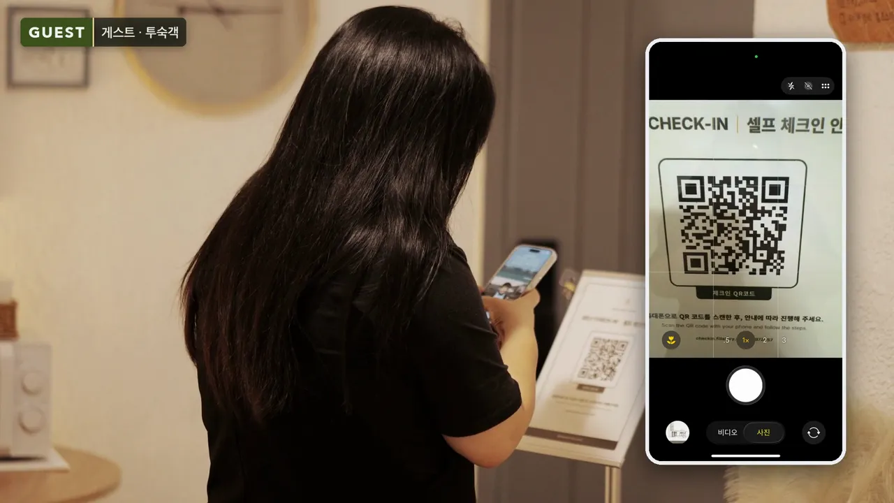 숙소 현관에 세워 둔 셀프 체크인 QR 안내판을 손님이 자기 휴대폰 카메라로 찍는 장면